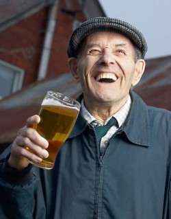 Laughing elderly man drinking glass of beer